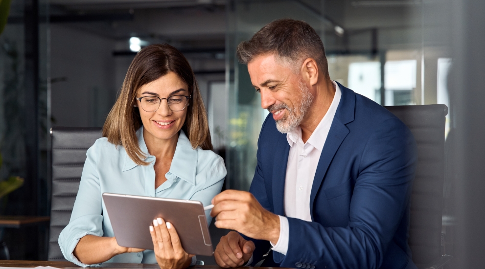 man and woman in office looking at ipad