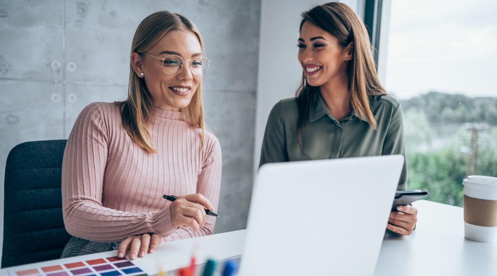 two woman at desk with computer