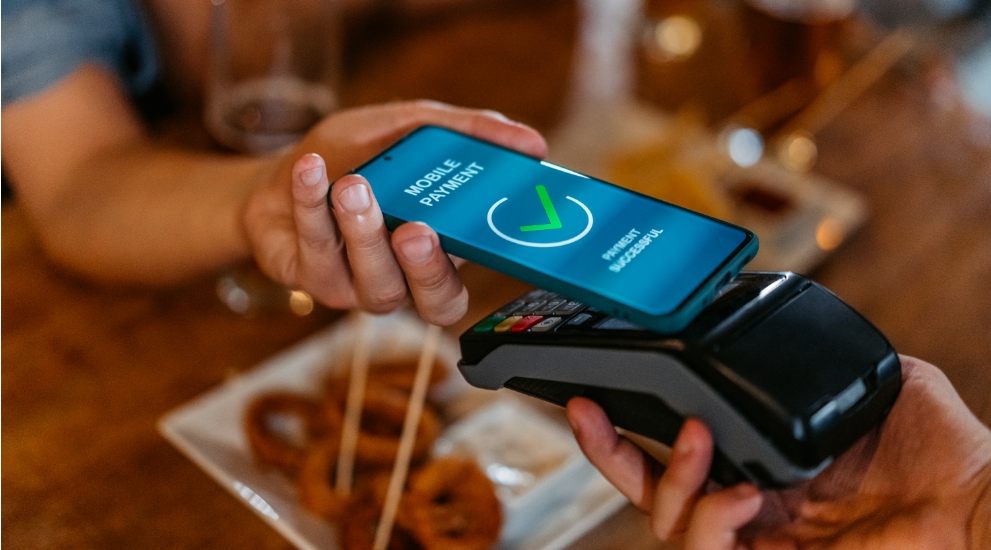 Two people paying with cell phone on merchant device